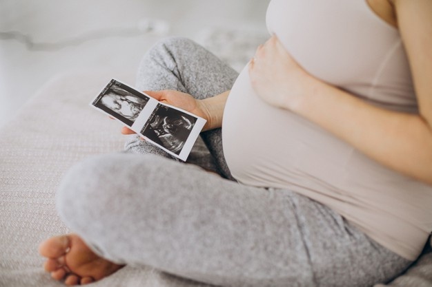 mujer-embarazada-foto-ultrasonido-sentada-cama